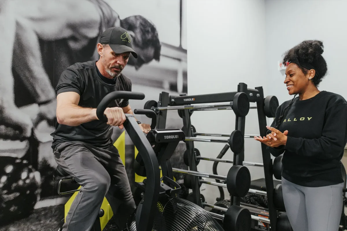 A coach checks in with a member during an air bike interval